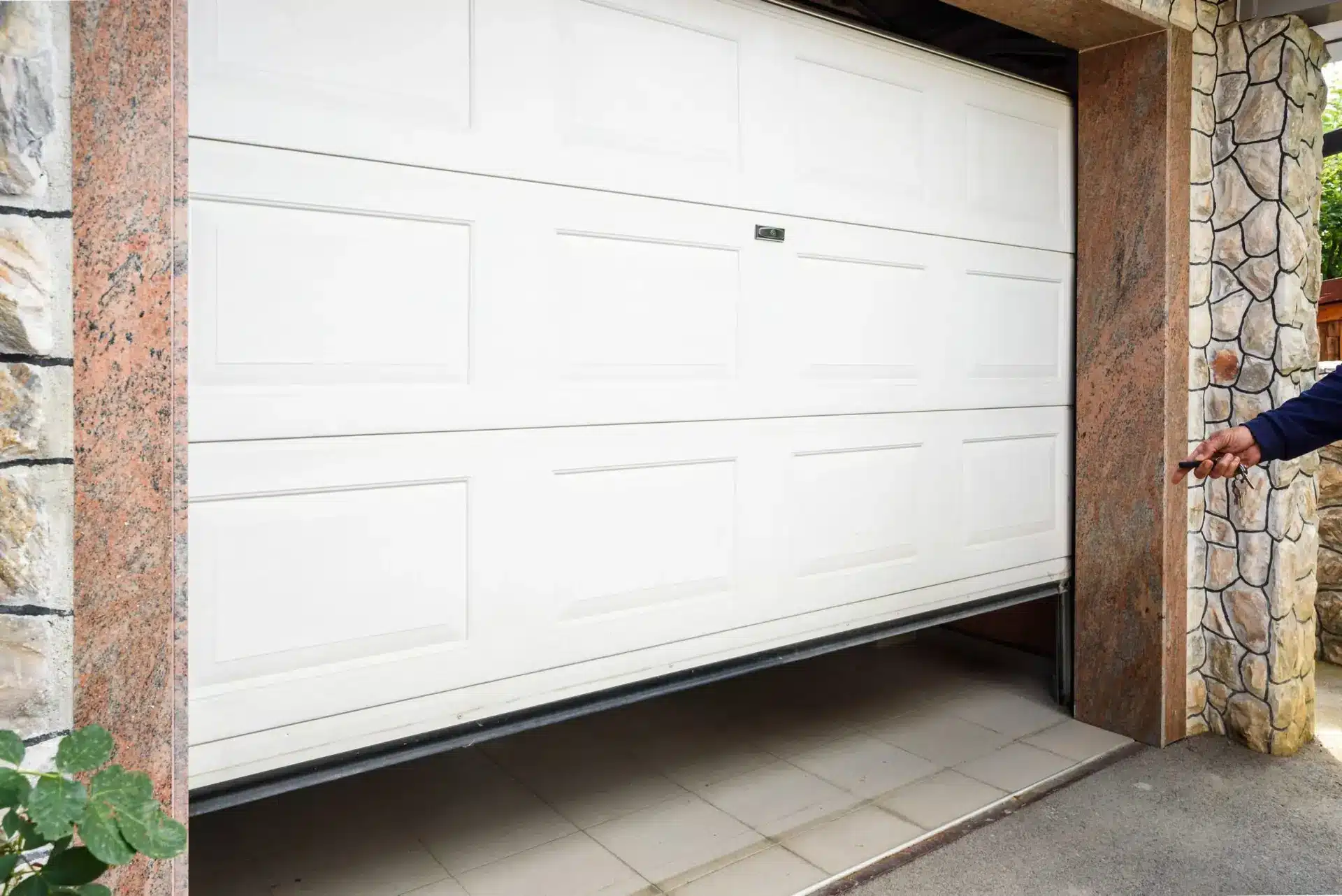 White electric garage door opening with remote control in residential driveway